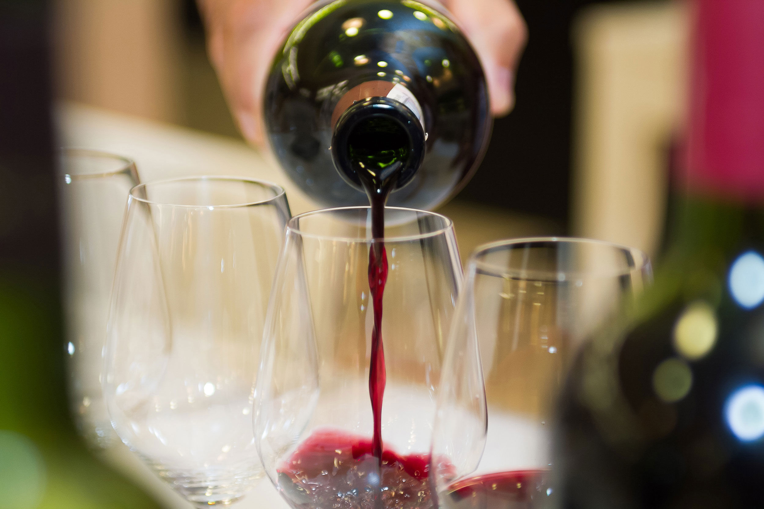 Kellner schüttet Rotwein in den Weingläsern.