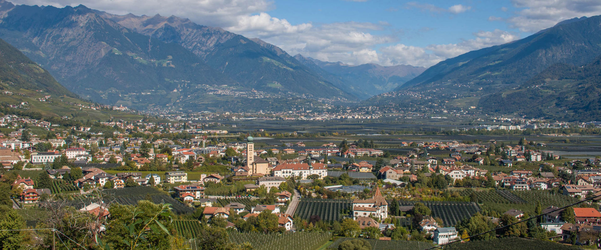 Lana bei Meran. Blick auf die Häuser, grüne Wein- und Obstgärten von Lana.