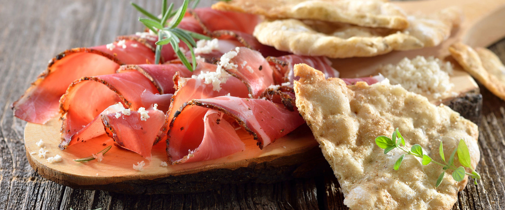 Schüttelbrot Schneidebrett aus Holz mit Speck, Kren und Schüttelbrot.