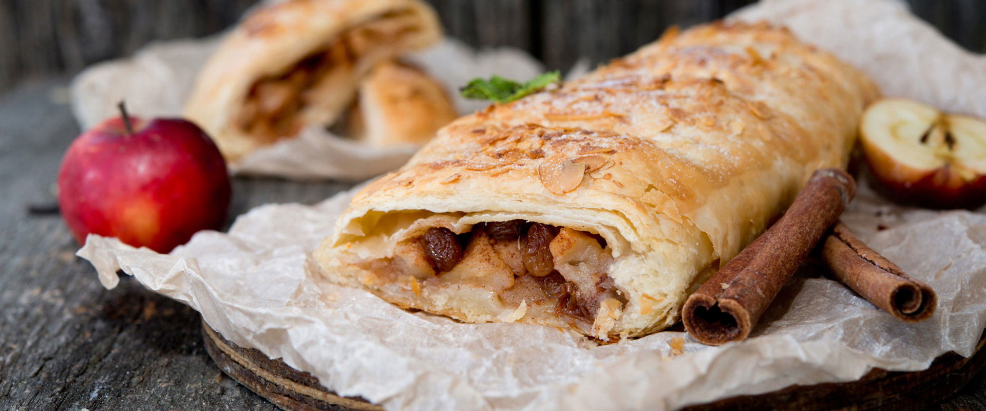Apfelstrudel Apfelstrudel, mit Zimtstangen und Äpfeln dekoriert.
