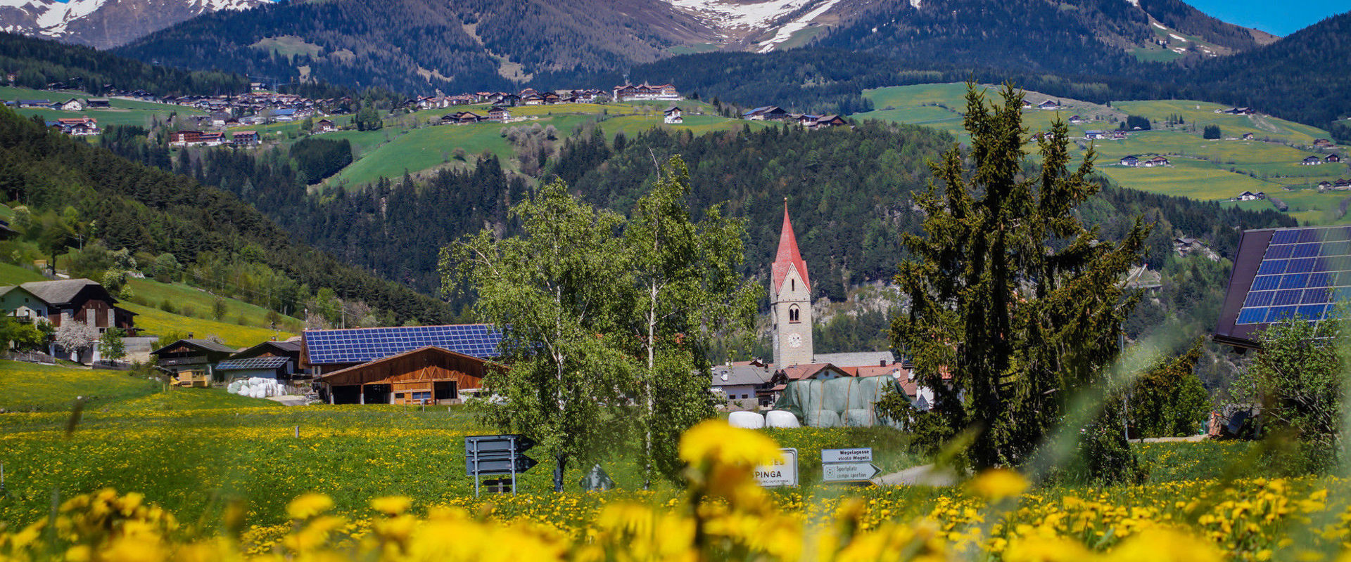 Spinges Blick auf Spinges mit Kirche im Frühling & Berge im Hintergrund