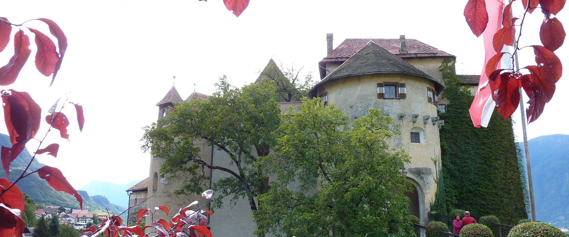 Schloss Schenna Zwischen Bäumen und Blättern sieht man Schloss Schenna.