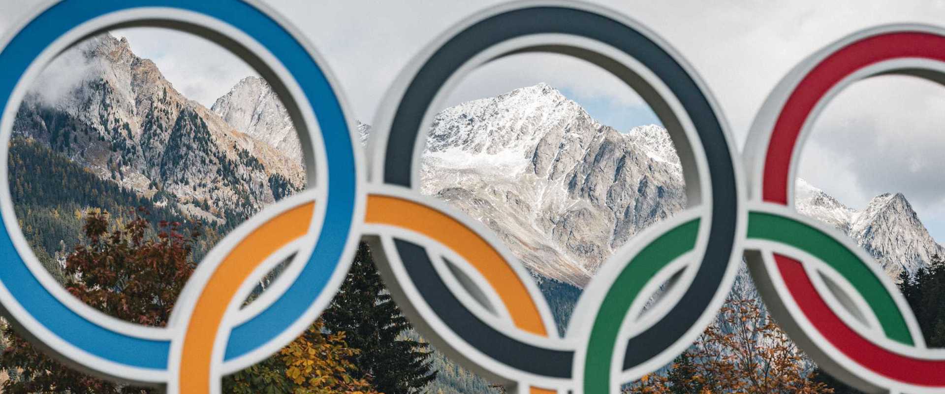 Die Olympischen Ringe in Antholz vor der herbstlichen Bergwelt mit schneebedeckten Gipfeln