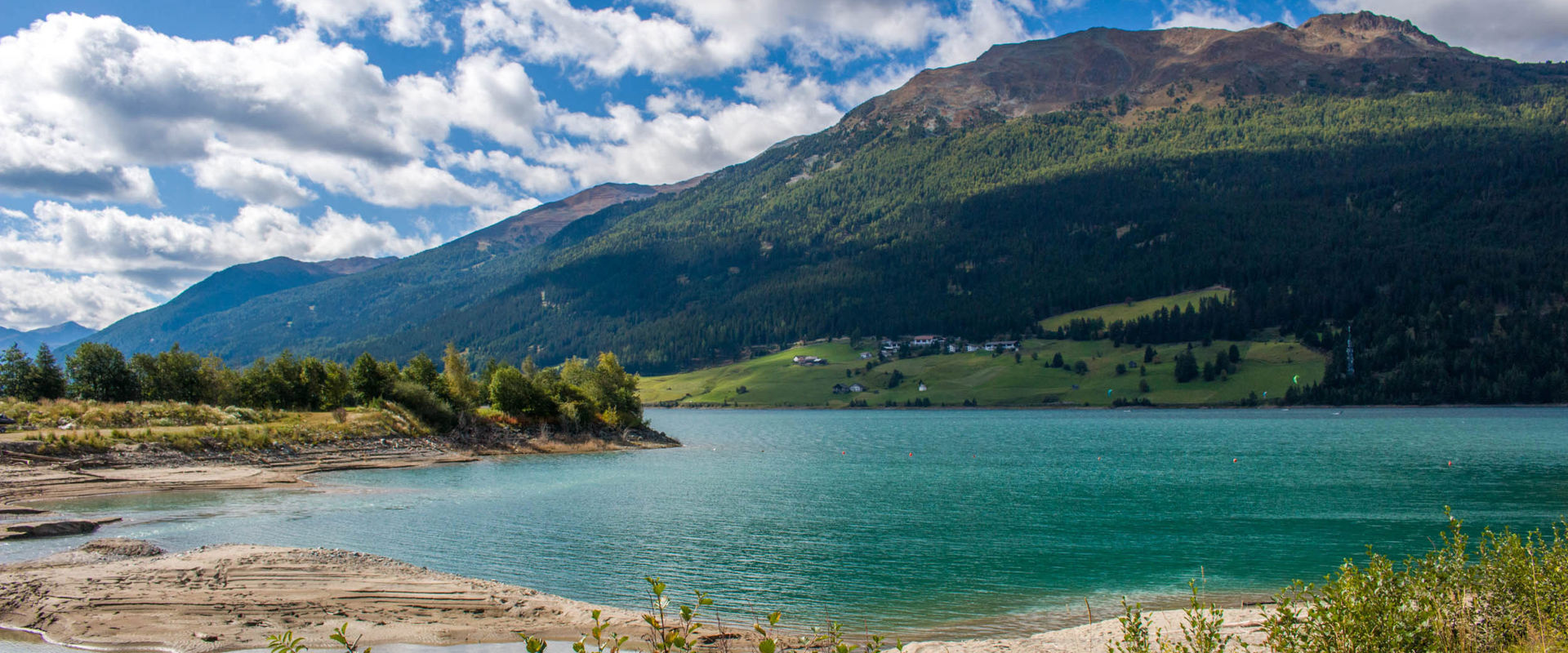 Graun am Reschensee Grün bewachsenes und sandiges Ufer des Reschensees bei Graun.