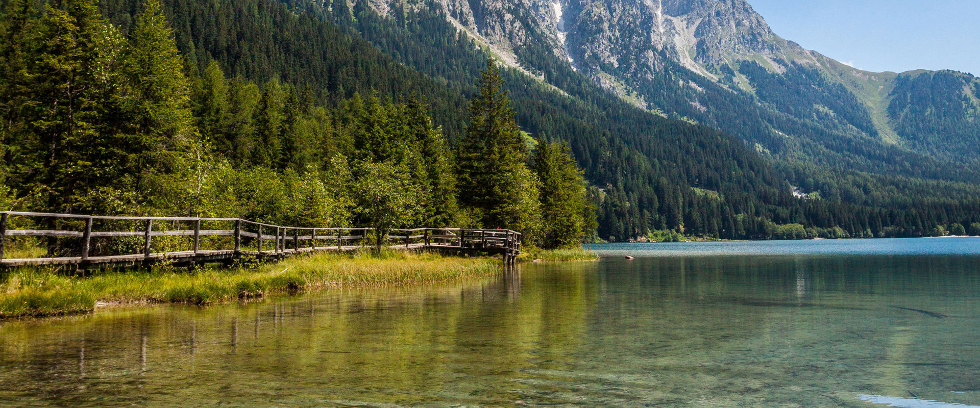 Bergsee Bergsee umgeben von dichten Wäldern und hohen Bergspitzen.