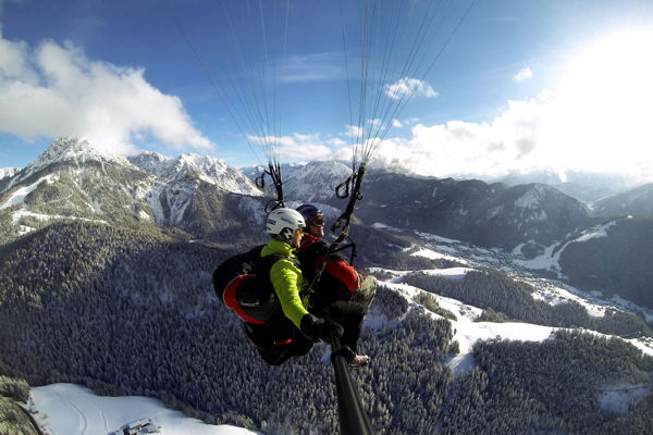 Tandem Gleitschirmfliegen über dem Kronplatz im Winter.