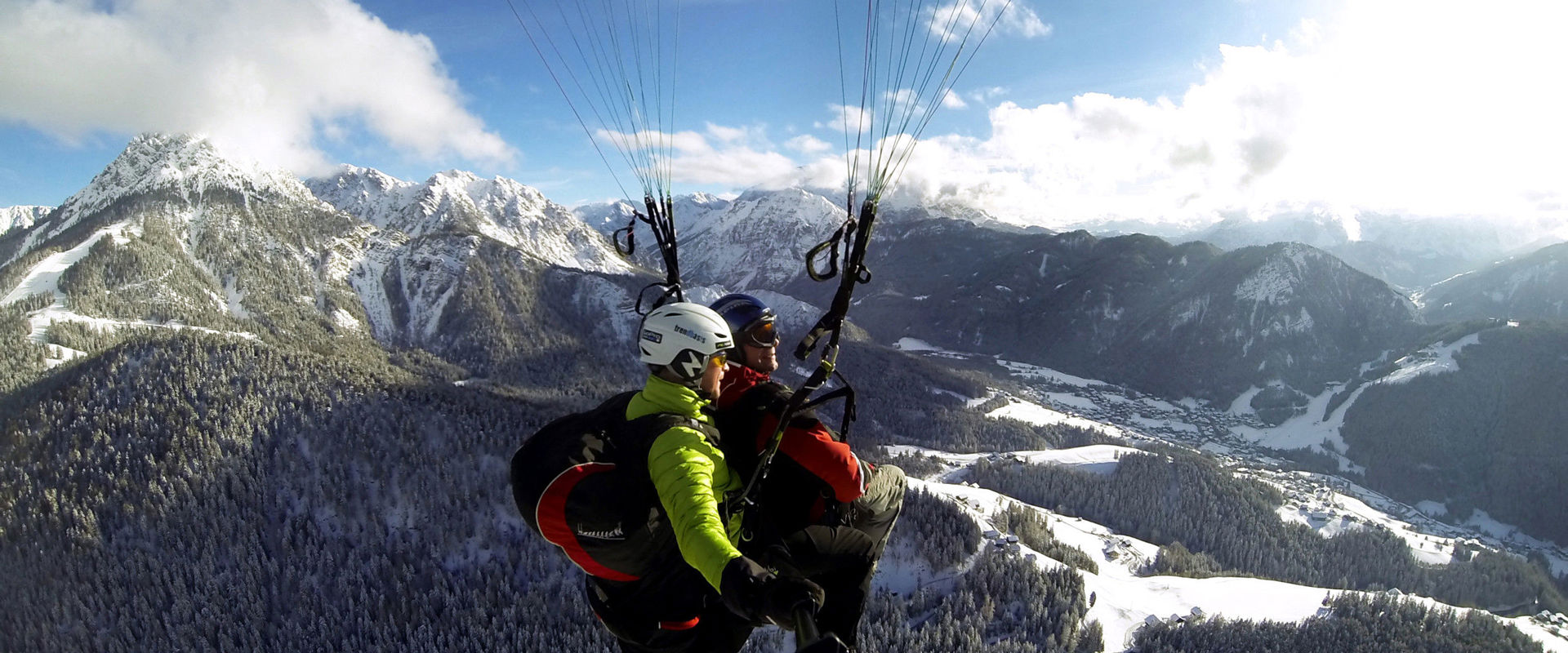 Tandem Gleitschirmfliegen über dem Kronplatz im Winter.