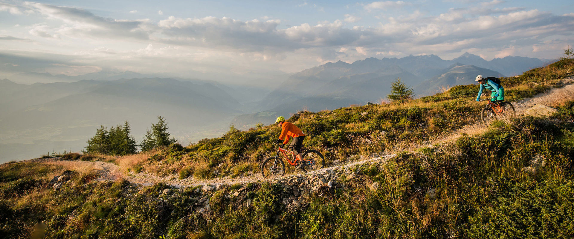Fahrradabfahrt Zwei Radfahrer fahren einen schmalen Steig den Berg hinab.