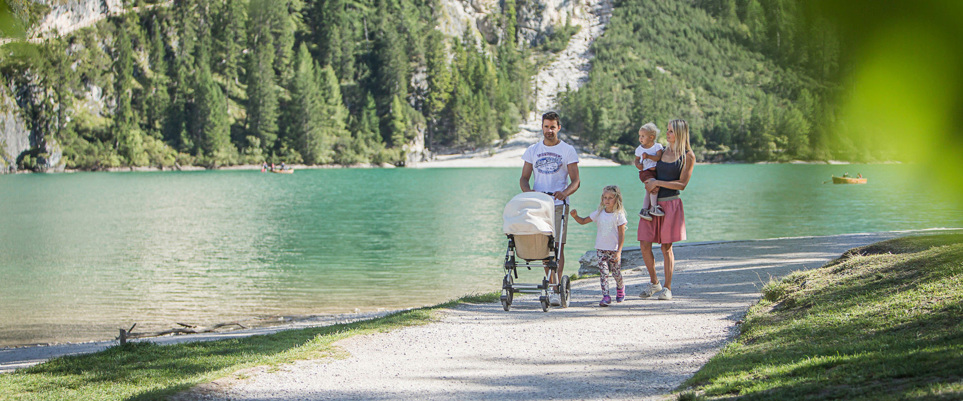 5-köpfige Familie spaziert am Seeufer mit dem Kinderwagen.