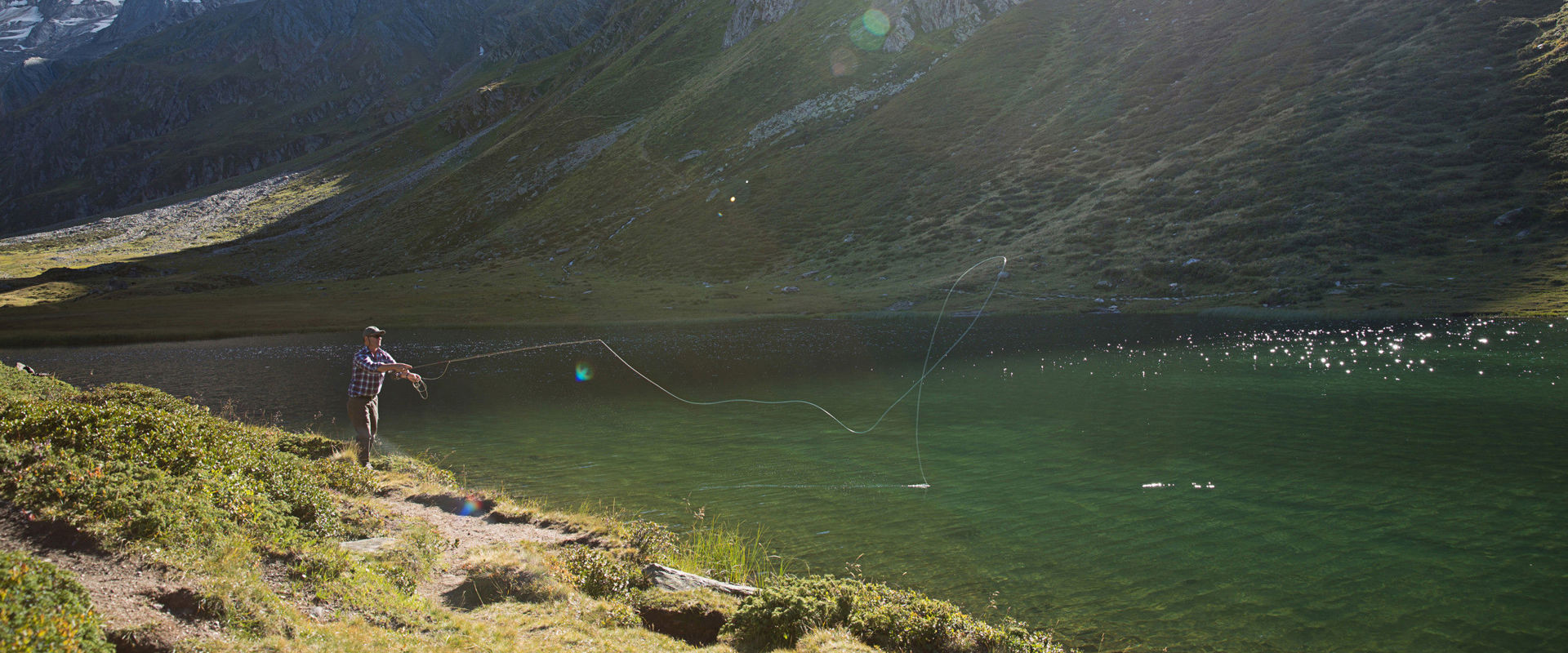 Fishing in the Passeier Valley Ein Mann angelt in einem Bergsee im Passeiertal.