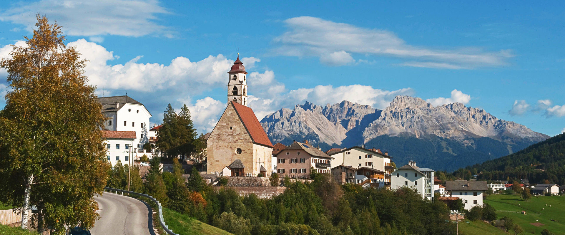 Deutschnofen Häuser und Kirche in Deutschnofen mit Bergen im Hintergrund