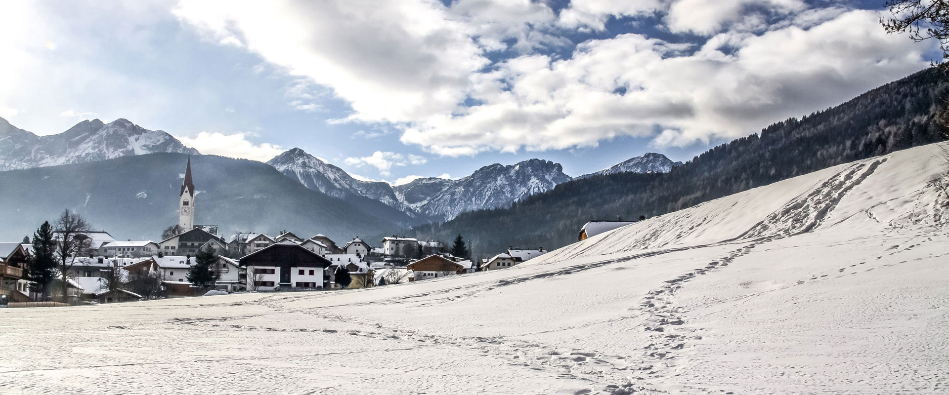 Blick auf Olang mit Dolomiten im Hintergrund im Winter