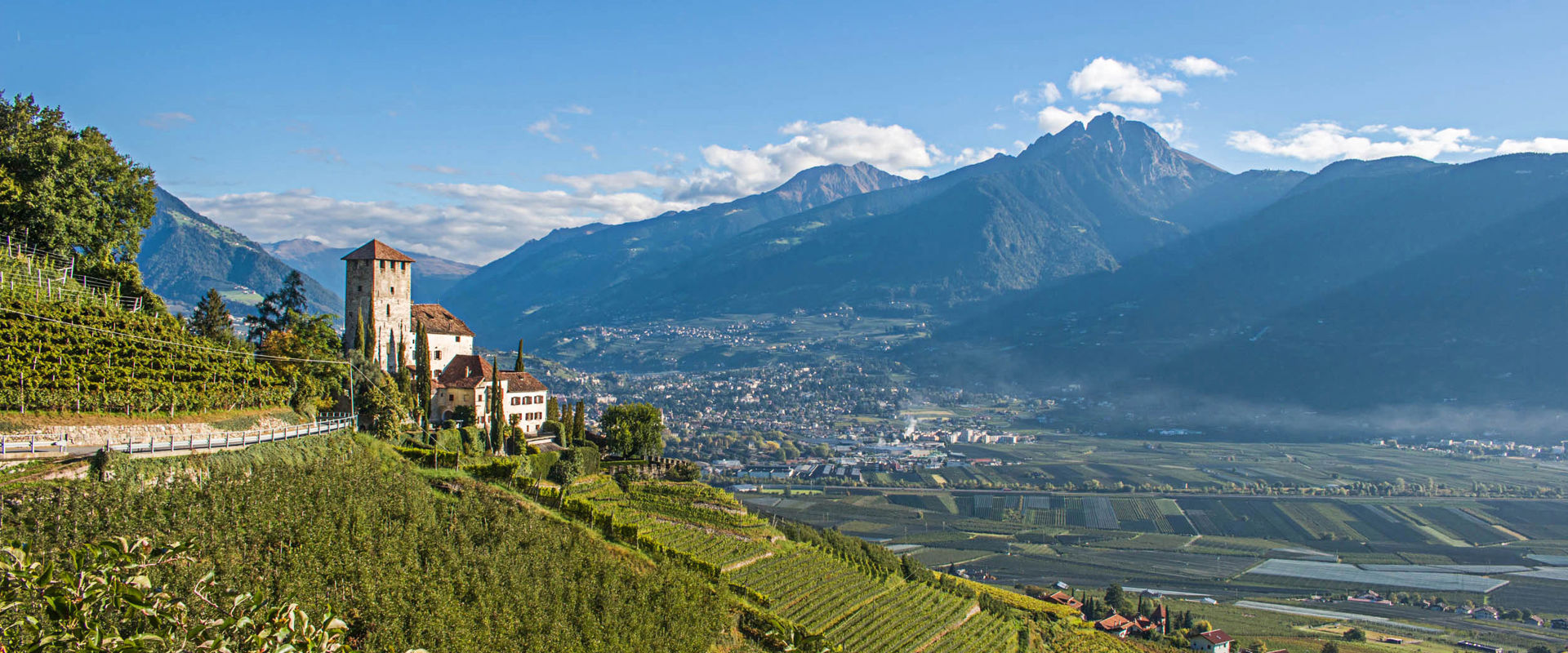 Schloss Lebenberg umgeben von Weinbergen und Apfelwiesen.