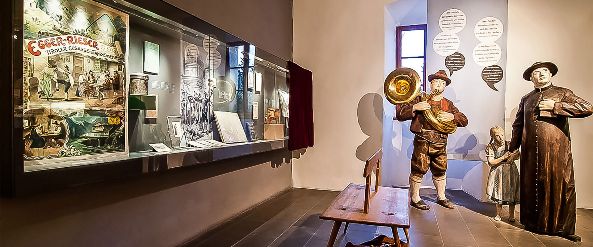 Menschengroße Holzfiguren und eine Vitrine mit verschiedenen ländlichen Gegenständen.