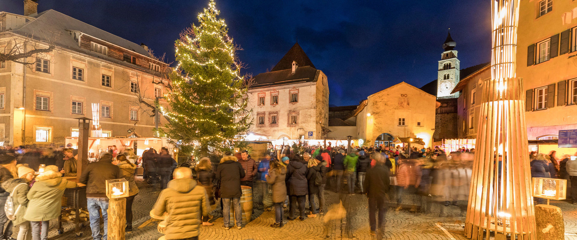 Dorfplatz Glurns in weihnachtlicher Stimmung. Belebter Dorfplatz in Glurns mit Weihnachtsbaum und Lichterketten.