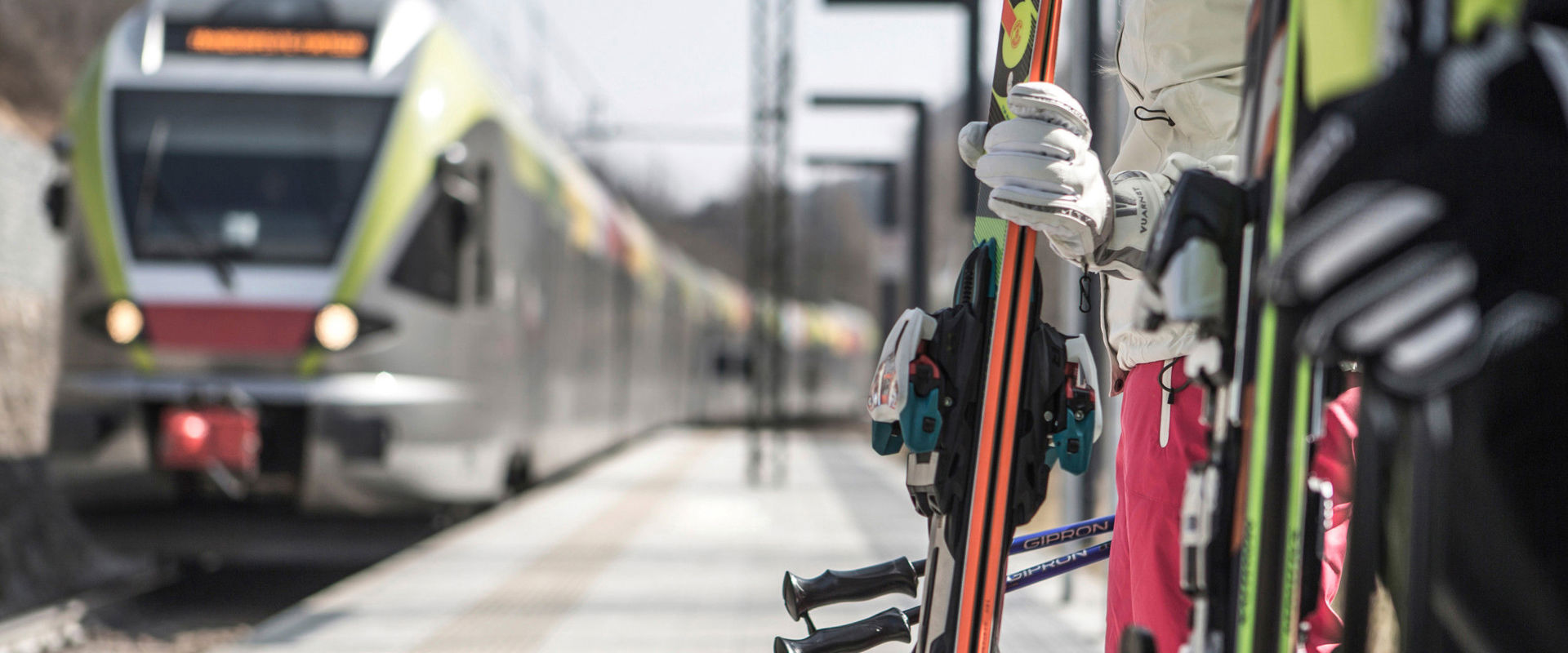Reisen mit Zug im Winter Skifahrer warten am Bahnsteig, während der Zug am Bahnhof einfährt.