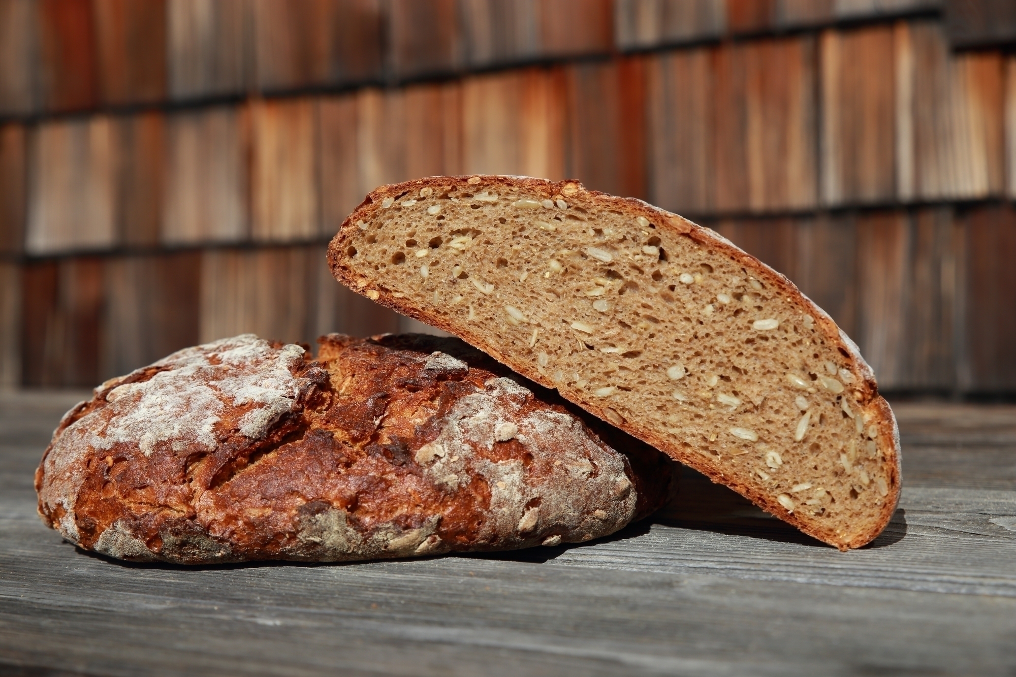 Ein ganzer und ein halber Laib Steinofenbrot liegen auf einem Holztisch vor der Brixner Hütte.