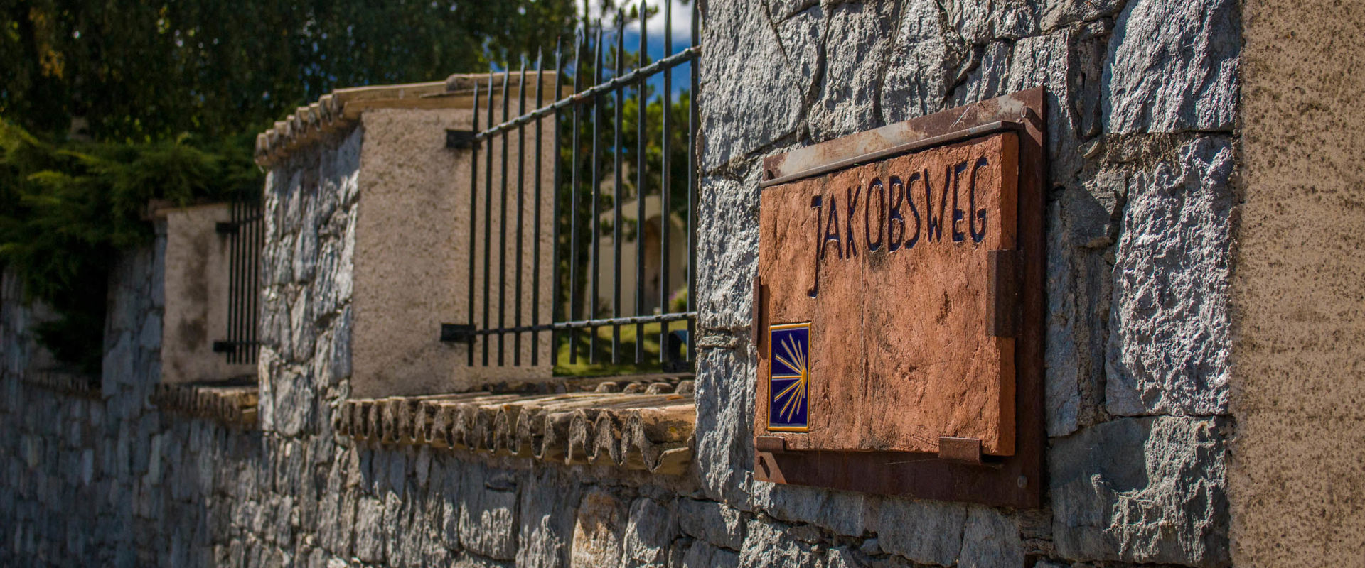 Der Jakobsweg durch Südtirol. Tonschild des Jakobsweges an einer Steinmauer.