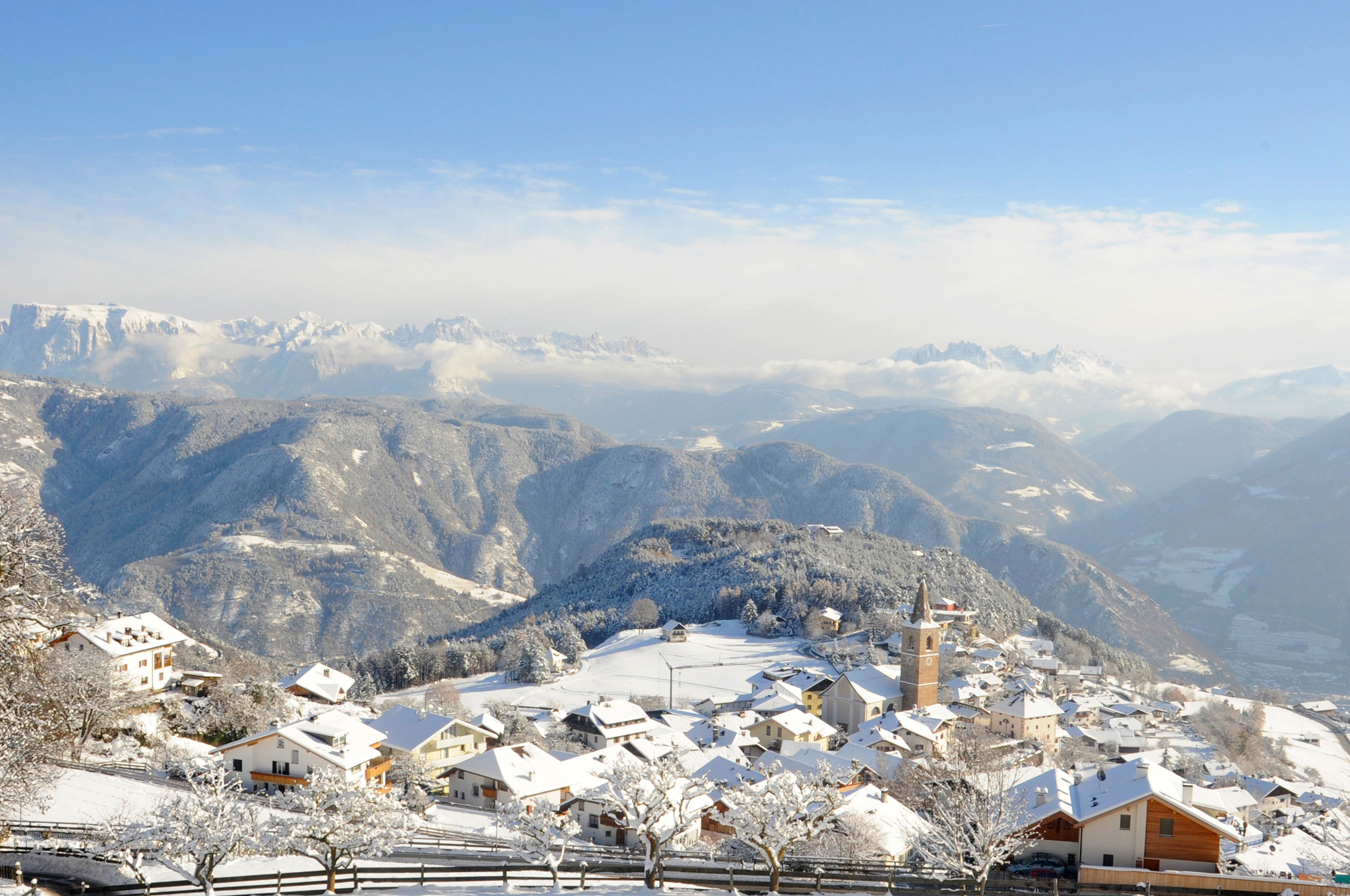 Jenesien von oben im Winter mit Ortszentrum und Kirche, Dolomiten im Hintergrund