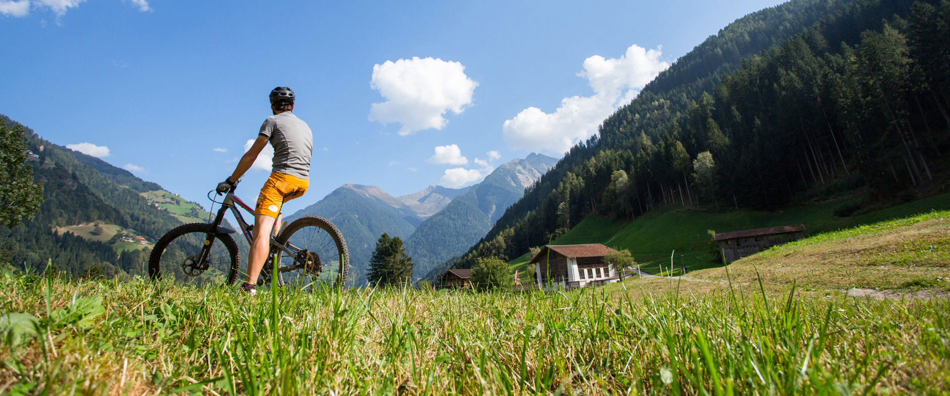 Mit dem Fahrrad auf dem Berg. Ein Mann sitzt auf dem Fahrrad und blickt in die Ferne zu den Bergspitzen.