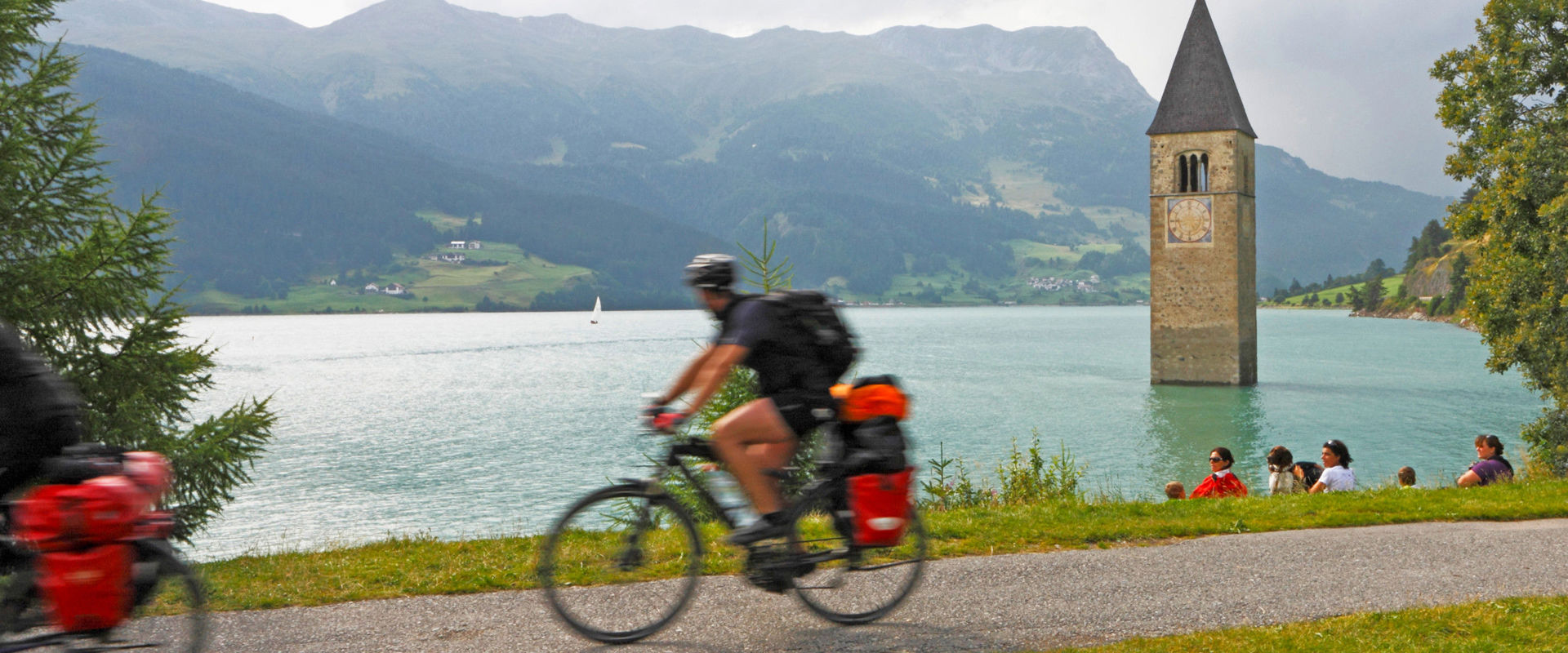 Radfahrer fährt am Reschensee vorbei.