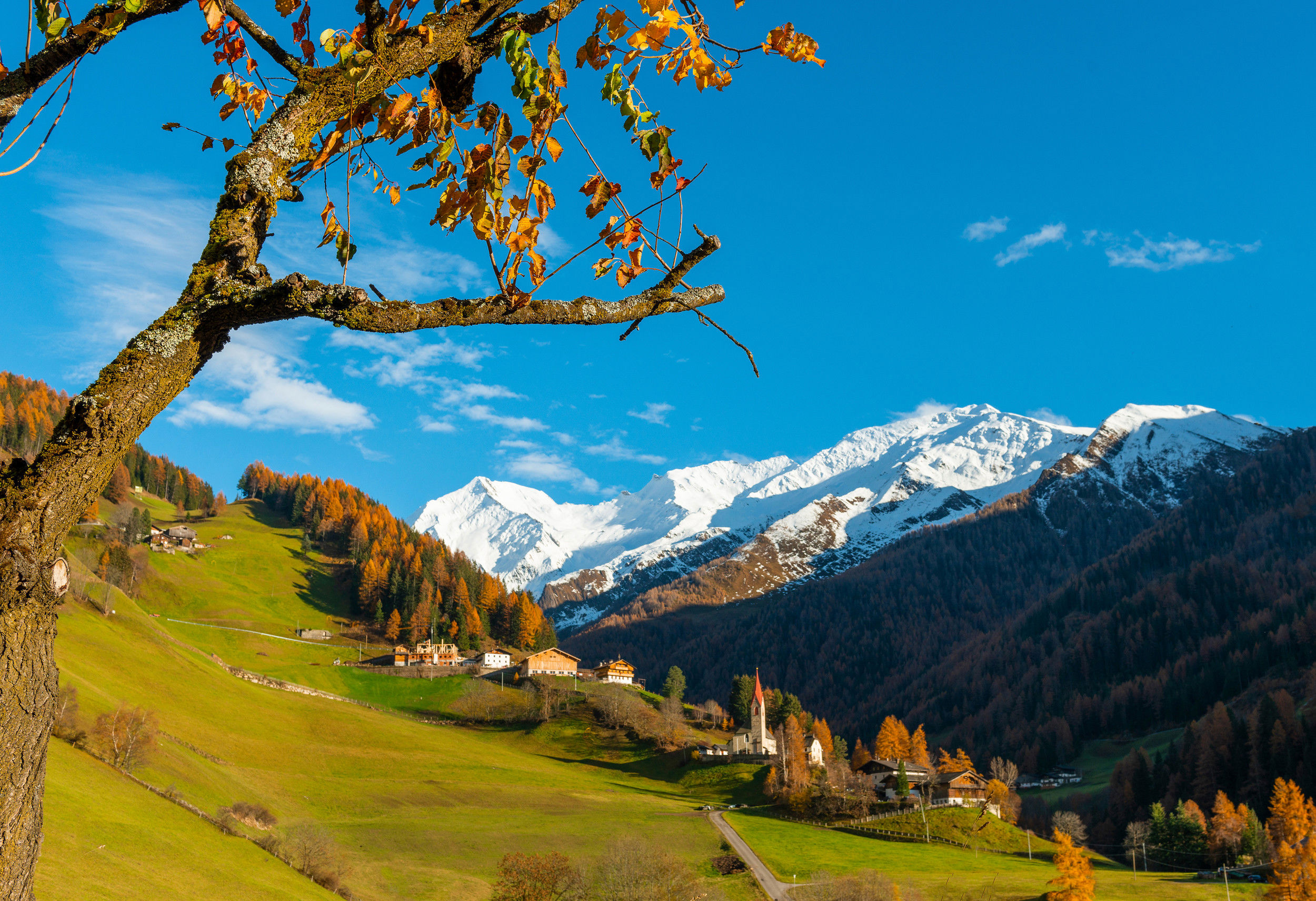 Das Dorf St. Peter im Ahrntal mit schneebedeckten Berggipfeln im Hintergrund