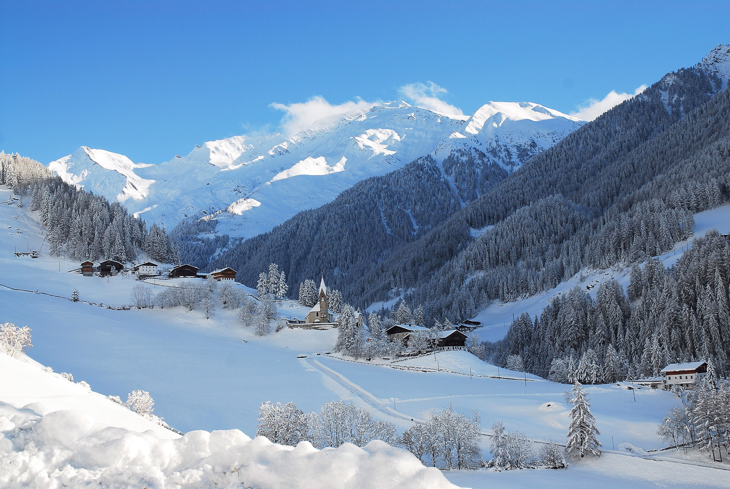 Blick auf einige Häuser in St. Peter im Ahrntal mit umliegender Schneelandschaft