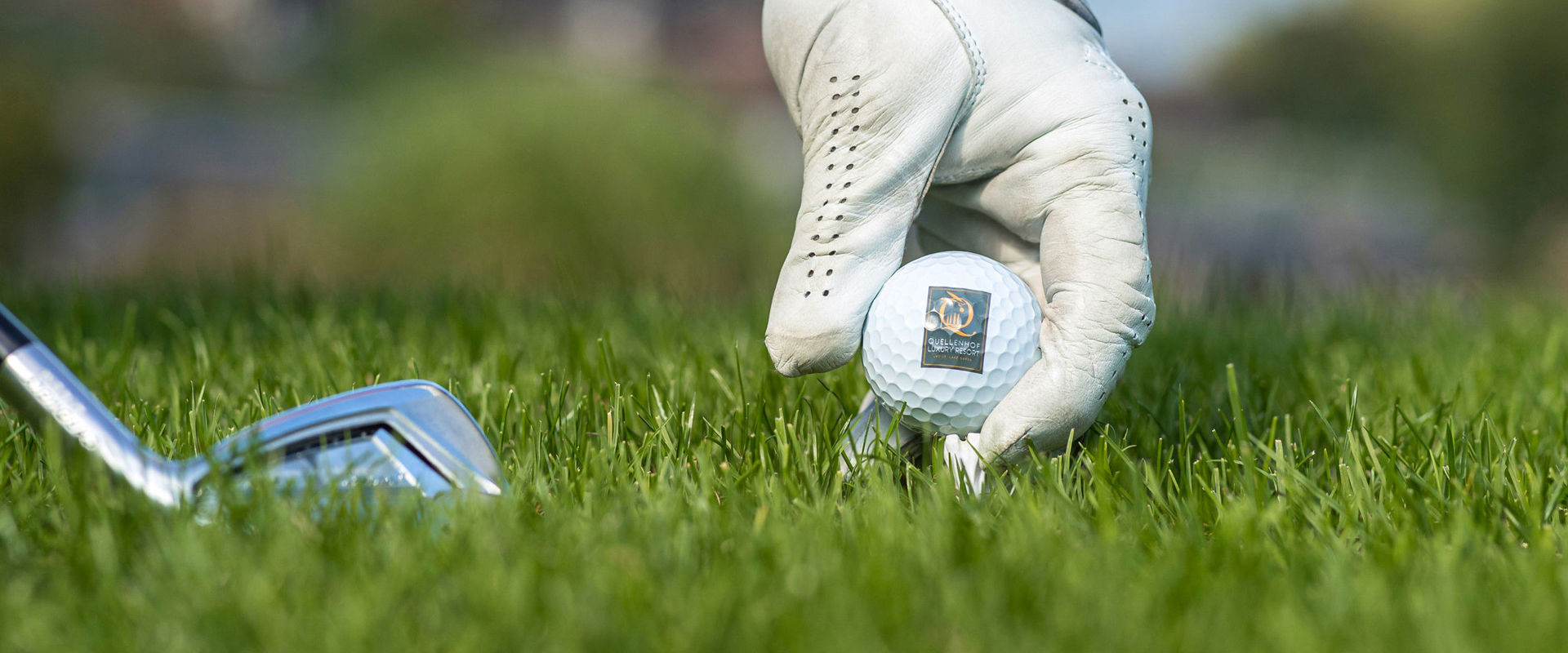 Golfplatz Quellenhof Hand platziert den Golfball auf den Rasen zum Abschlag.