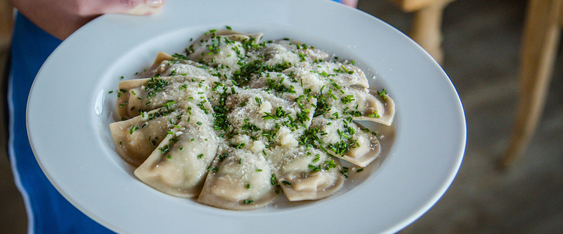 Kellnerin bringt Teller mit Schlutzkrapfen.