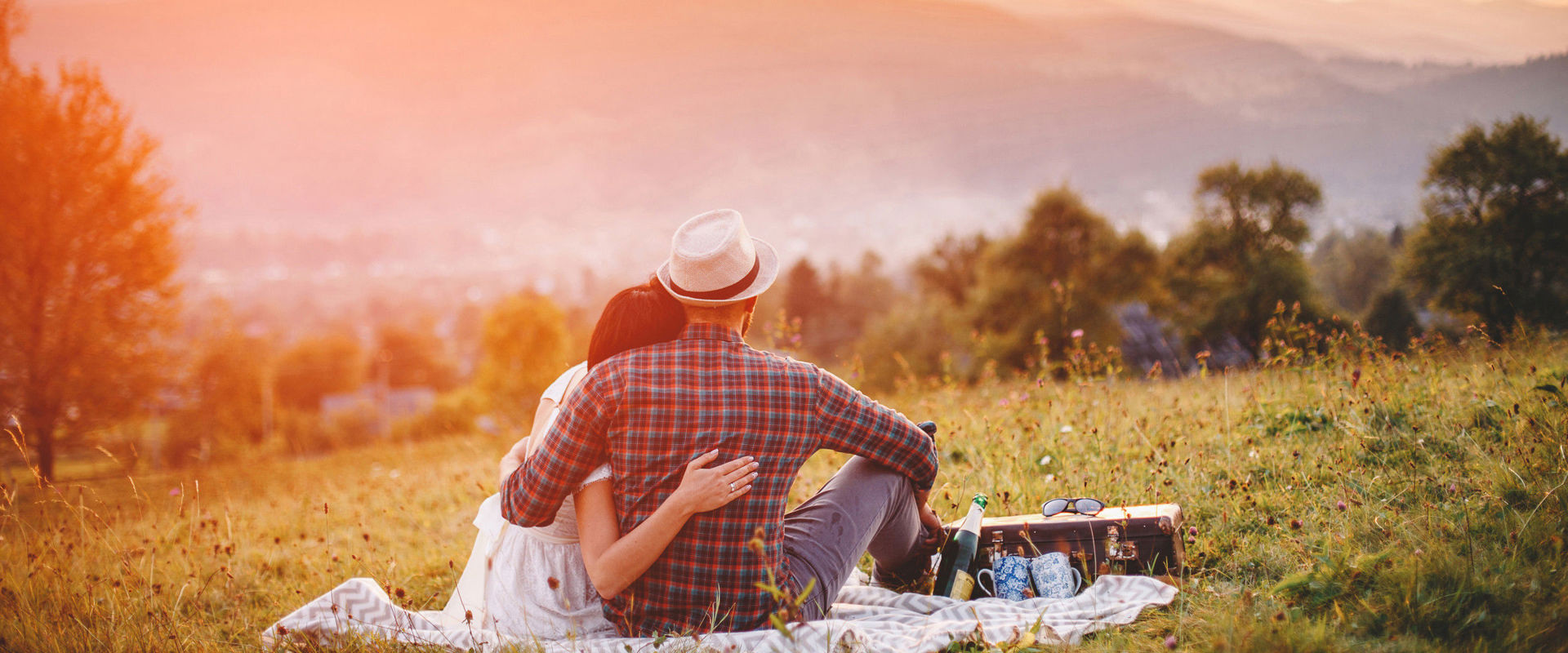 Verliebtes Paar Verliebtes Paar picknickt auf einer Blumenwiese bei Sonnenuntergang.