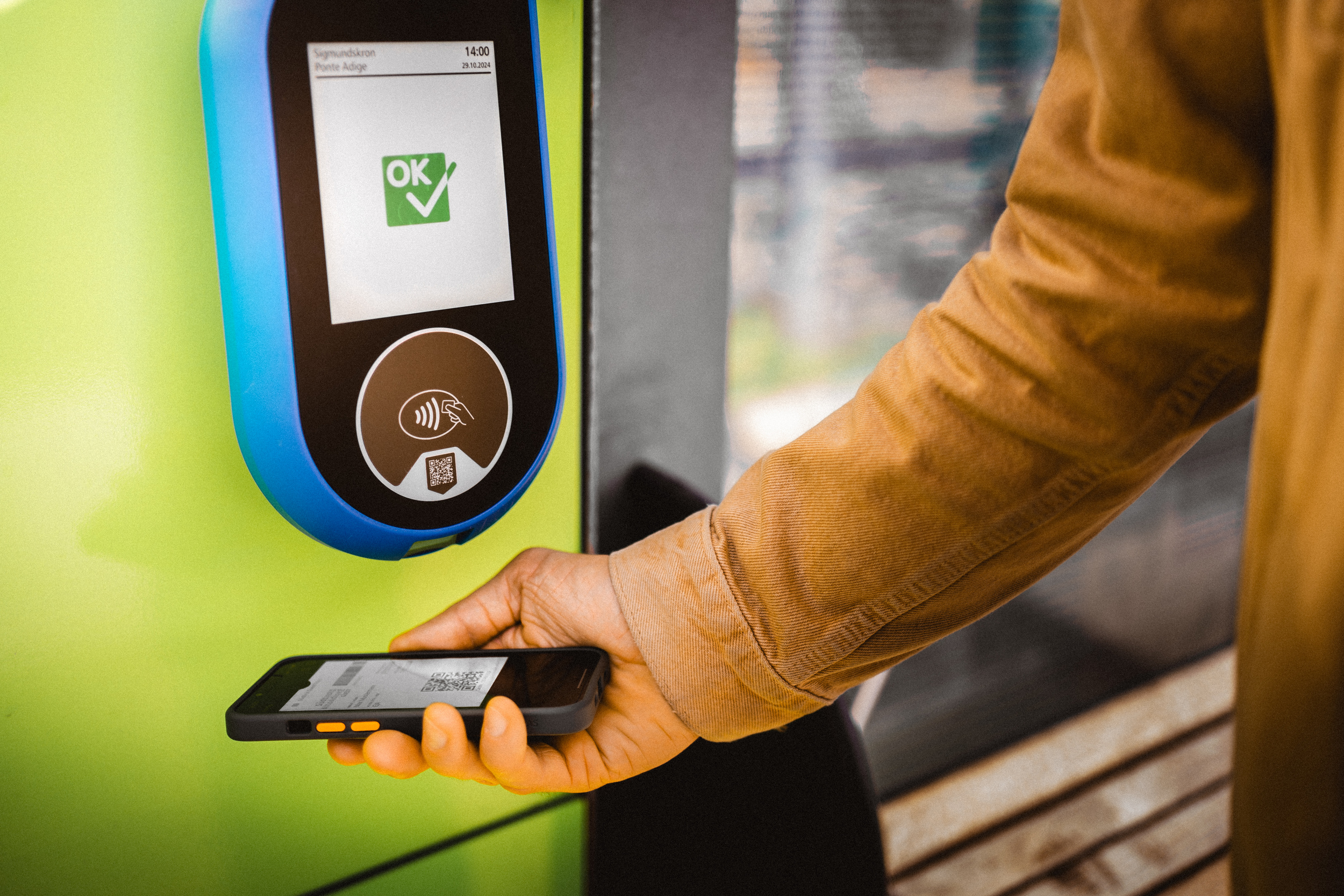 Hand hält Karte auf Mobiltelefon für öffentliche Verkehrsmittel zum Entwerten an ein Gerät