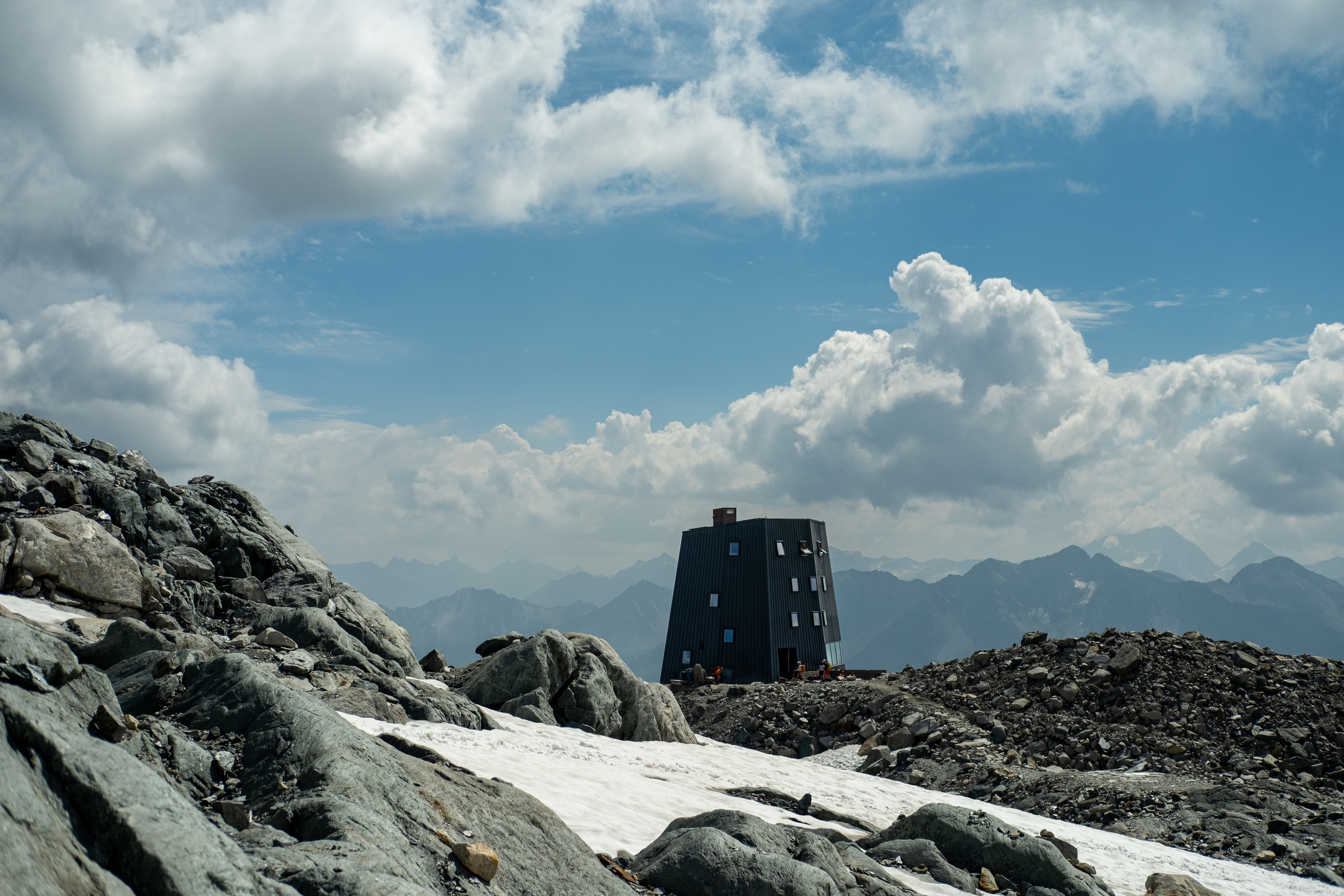 Moderne Berghütte in karger Berglandschaft mit Schneefeldern
