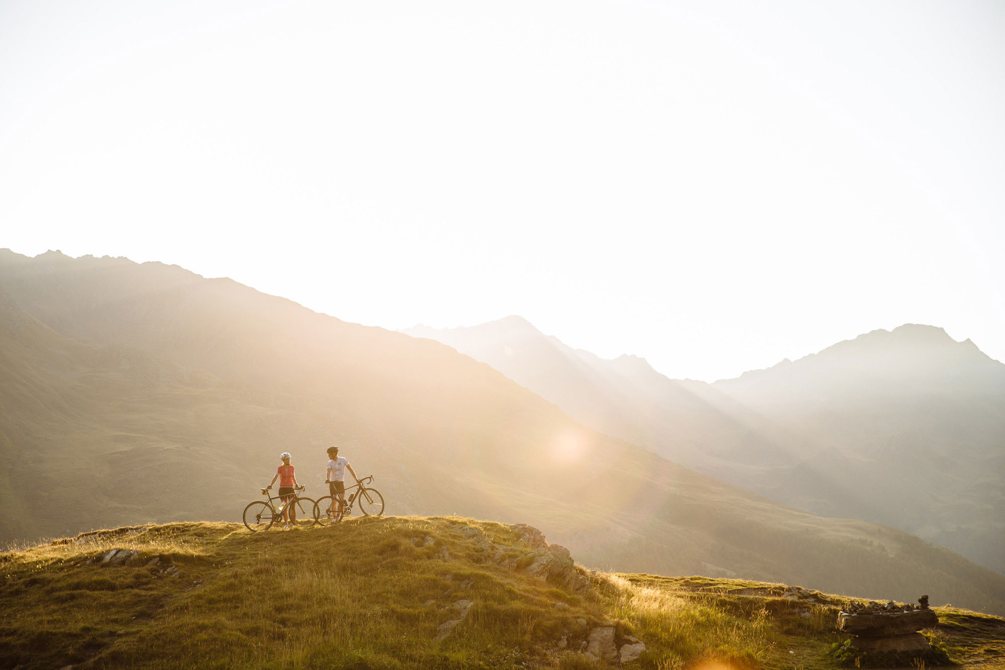 2 Radfahrer stehen inmitten einer atemberaubenden Berglandschaft.