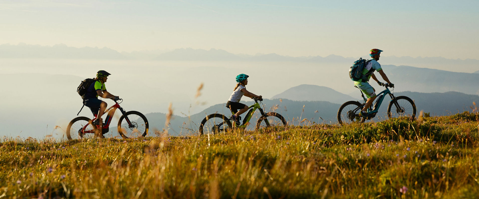 3 Menschen fahren mit einem E-Bike den Berg hoch.