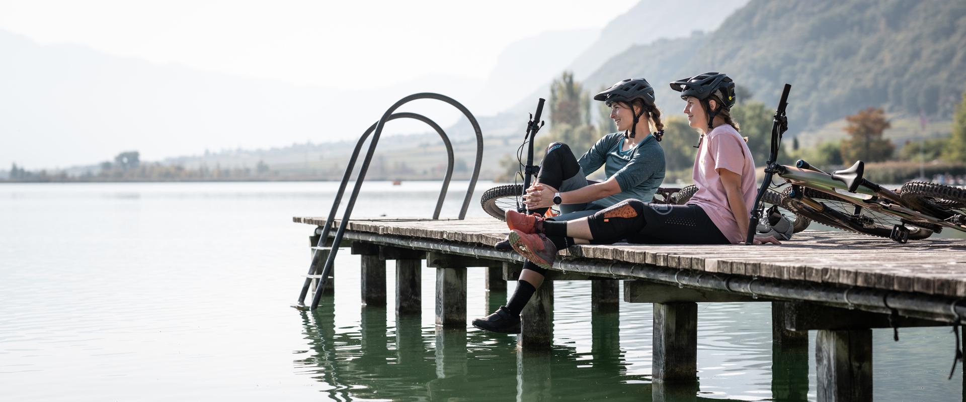 2 Radfahrerinnen auf dem Steg eines Sees in Südtirol