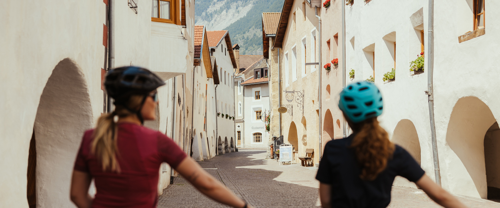 Zwei Radfahrerinnen im historischen Stadtzentrum von Glurns