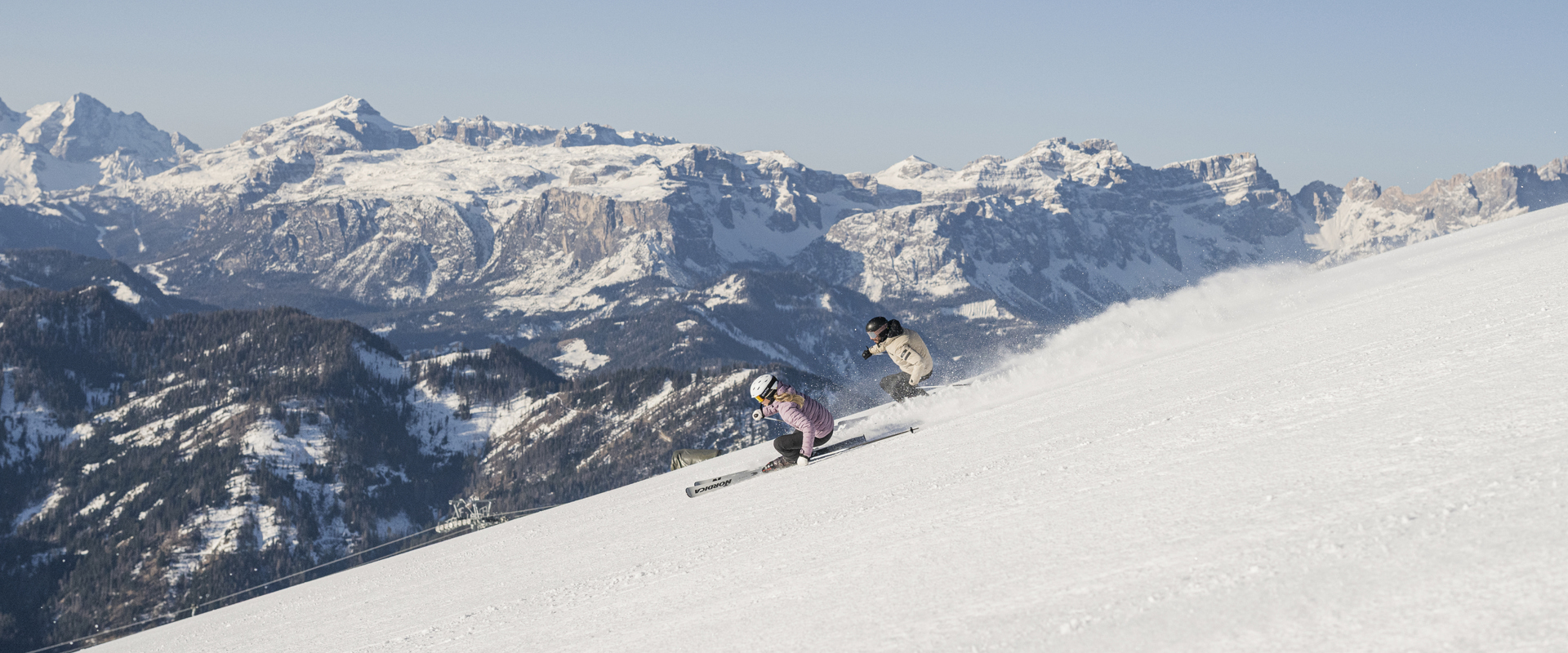 2 Skifahrer fahren die frisch präparierte Piste hinunter.