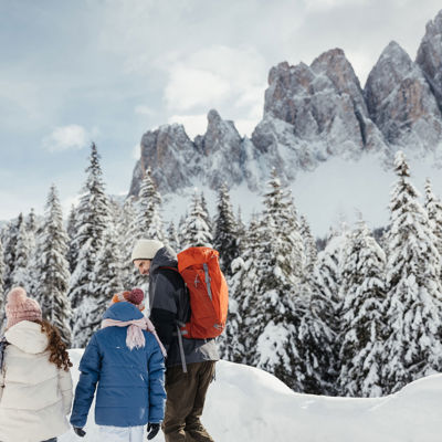 Vater wandert mit seinen Kindern in einer winterlichen Schneelandschaft.