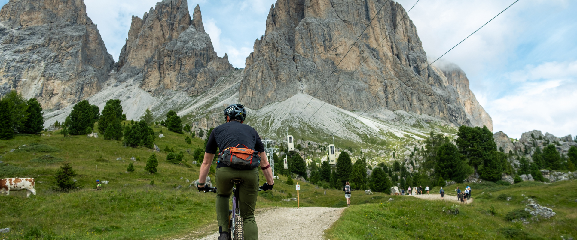 Mountainbiker unter Seilbahn und vor den Dolomiten