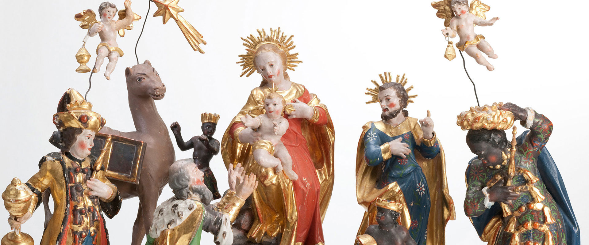 Geschnitzte Figuren einer Krippe. Im Zentrum Maria und Joseph mit dem Christuskind.