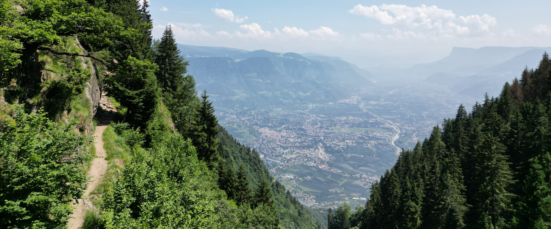 Meraner Höhenweg bei Algund Schmaler Wanderweg an bewaldetem Berghang, weiter Blick auf das Tal darunter