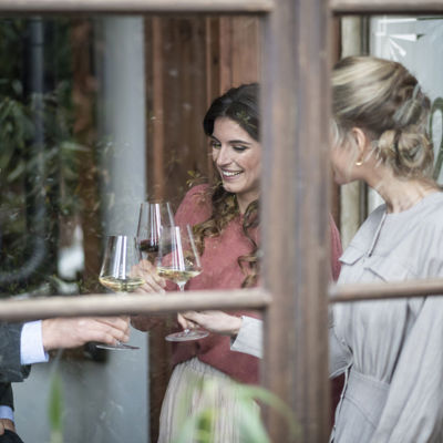 Drei Freunde trinken ein Glas Weißwein am Fenster in einer Bar.