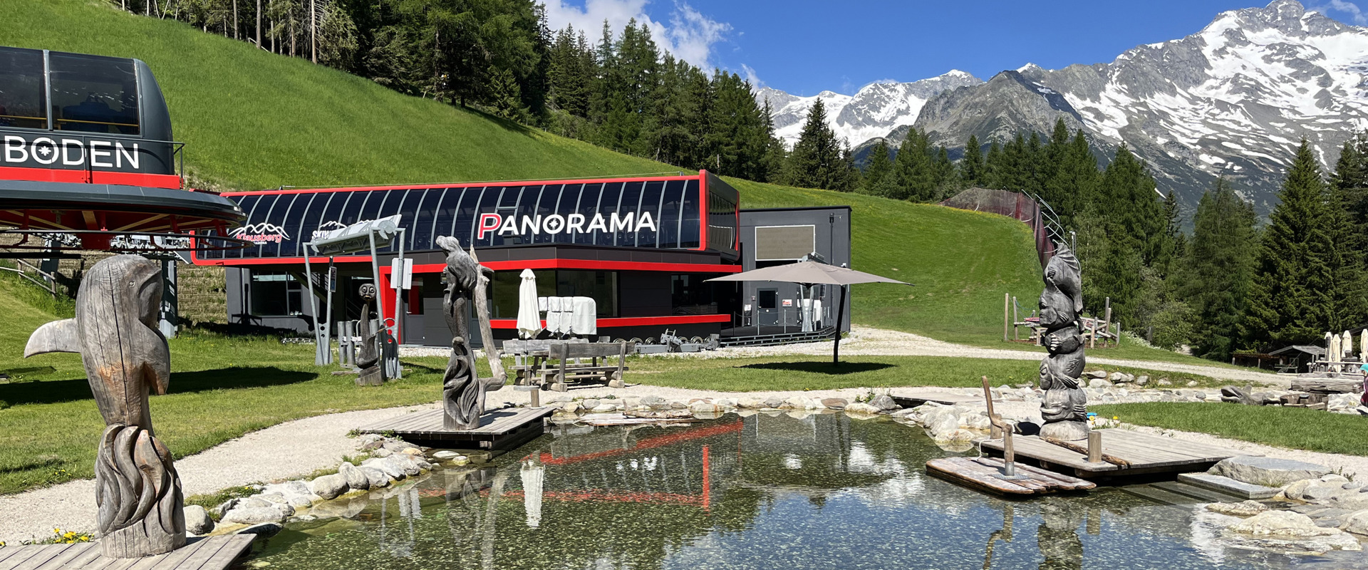 Klausiland Seilbahnstation mit Teich und geschnitzten Figuren