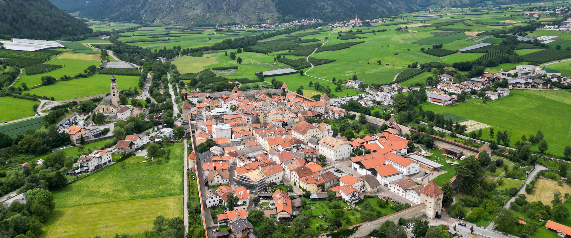 Blick von oben auf eine kleine Stadt, umgeben von einer alten Stadtmauer mit Türmen