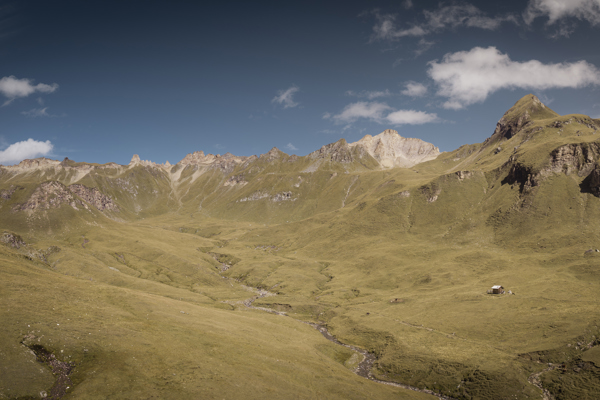 Sanfte Bergwiesen, Hütte und Bergspitzen am Horizont