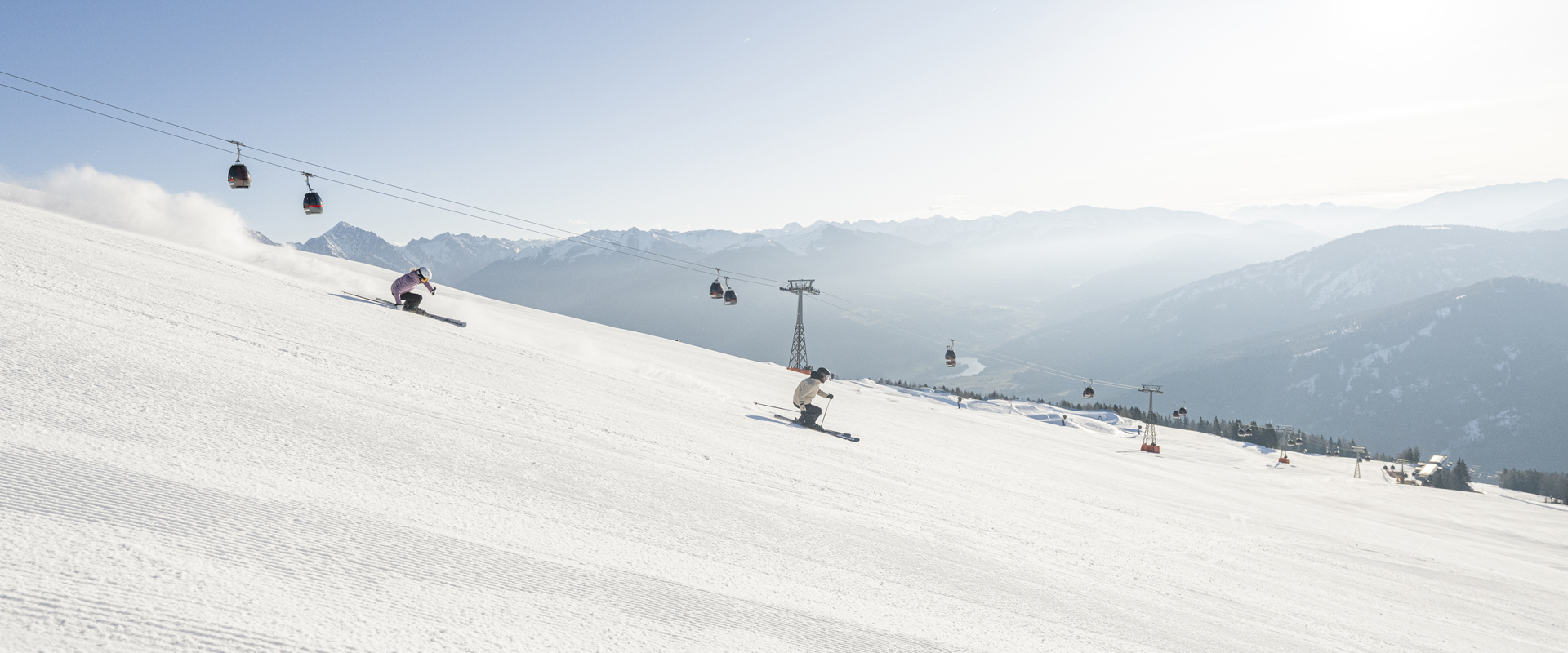 2 Skifahrer fahren die frisch präparierten Skipiste hinunter.