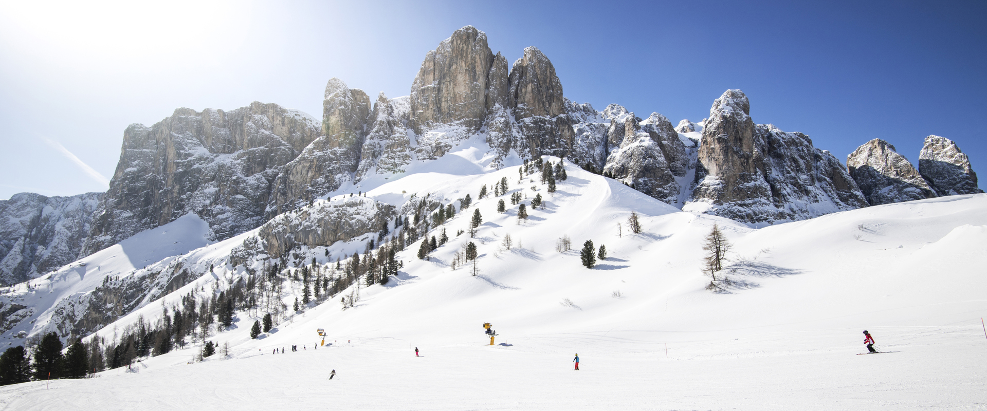 Skifahren bei strahlendem Sonnenschein mit Dolomitengipfeln